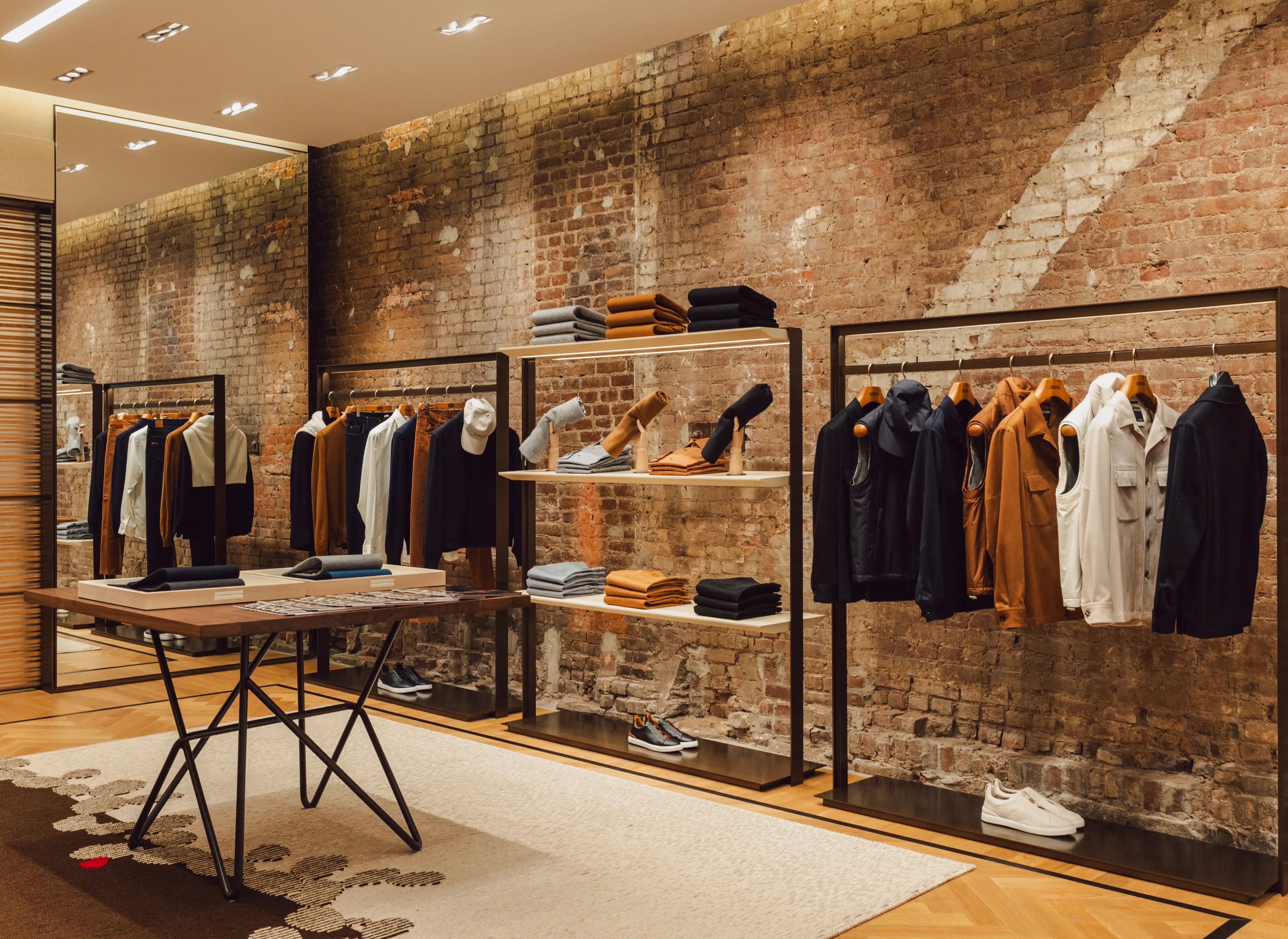 Interno di una boutique ZEGNA con scarpe, borse e capi d’abbigliamento elegantemente disposti sugli scaffali.